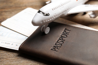 Photo of Passport with tickets and toy plane on wooden table, closeup. Travel agency