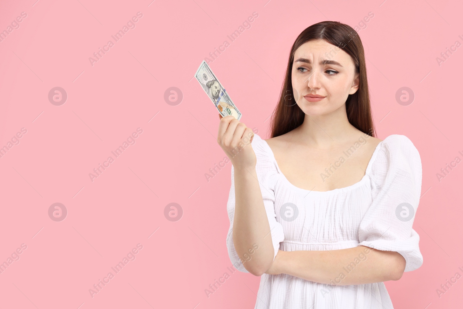 Photo of Sad woman with dollar banknote on pink background, space for text