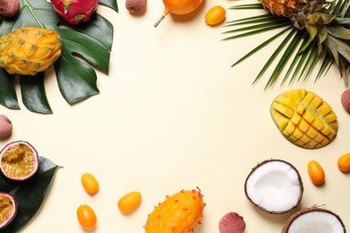 Frame of different exotic fruits on beige background, flat lay. Space for text