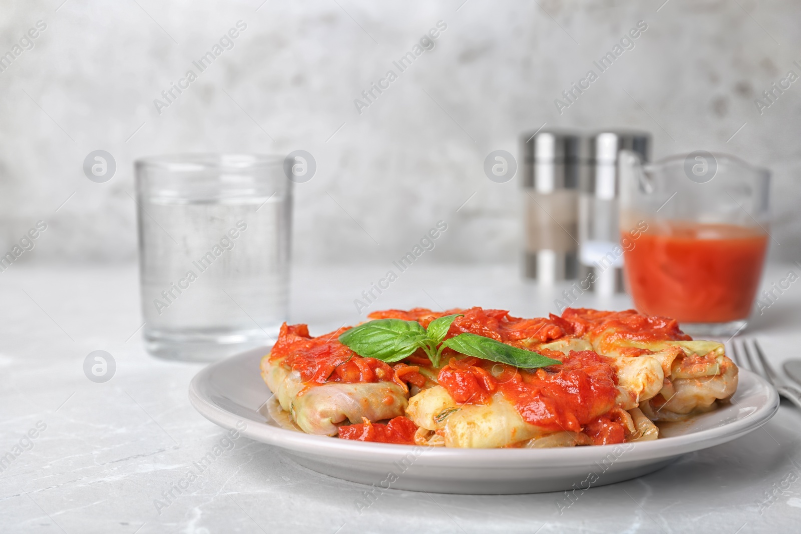 Photo of Plate with stuffed cabbage leaves in tomato sauce on table