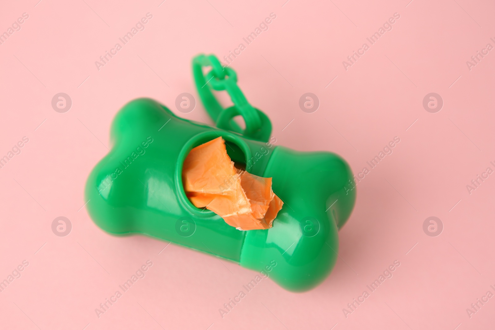 Photo of Dispenser with dog waste bags on pink background, closeup. Space for text