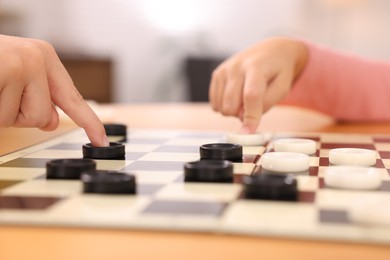 Photo of Children playing checkers at table indoors, closeup