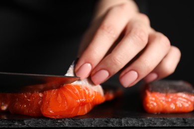 Photo of Chef removing scales from salmon for sushi at dark table, closeup