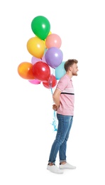 Young man holding bunch of colorful balloons on white background