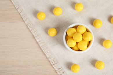 Photo of Tasty lemon drops on wooden table, flat lay