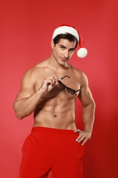 Sexy shirtless Santa Claus on red background