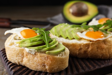 Photo of Delicious avocado sandwiches on wooden board, closeup