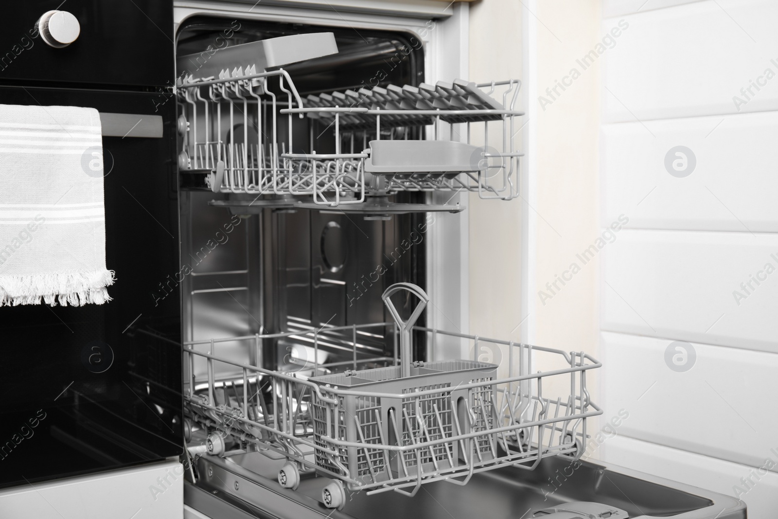 Photo of Open clean modern empty automatic dishwasher machine in kitchen