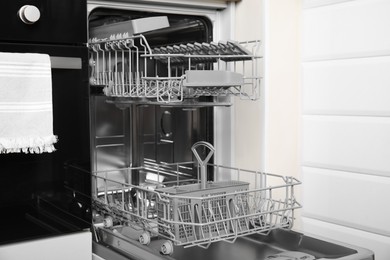Open clean modern empty automatic dishwasher machine in kitchen