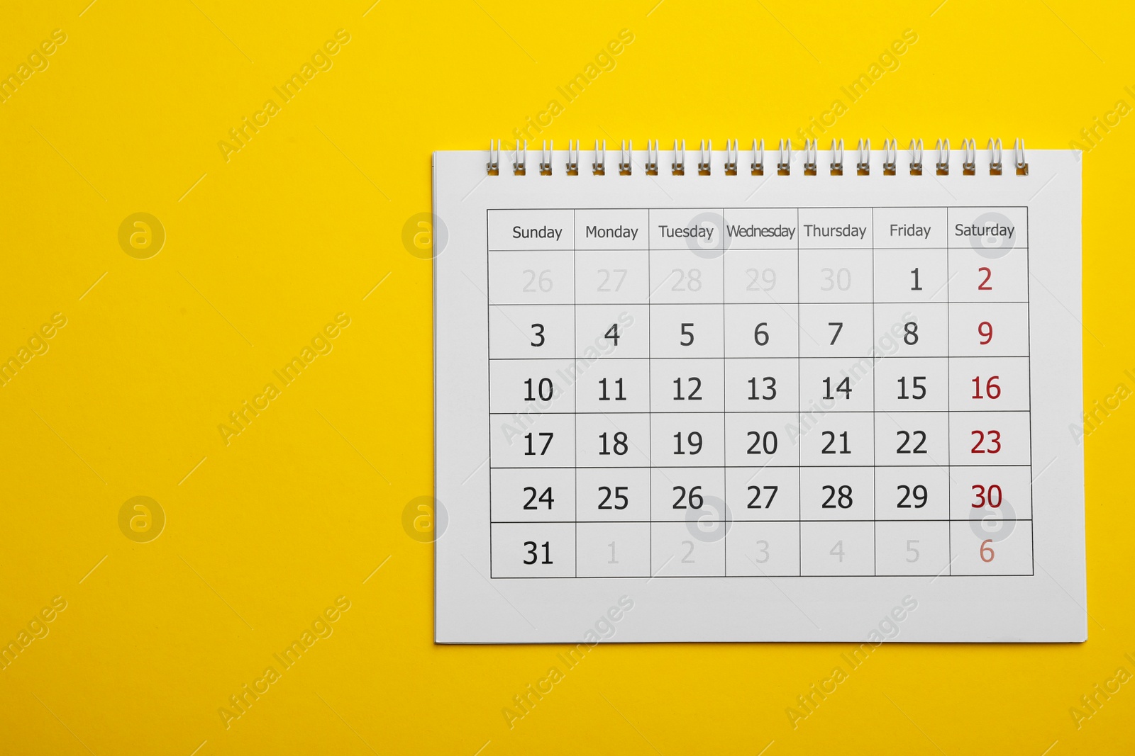 Photo of Paper calendar on yellow background, top view. Space for text