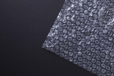 Photo of Transparent bubble wrap on black background, top view. Space for text