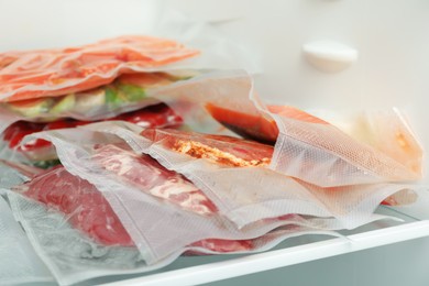 Photo of Vacuum bags with different products in fridge, closeup. Food storage