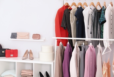 Photo of Racks with clothes in stylish dressing room interior