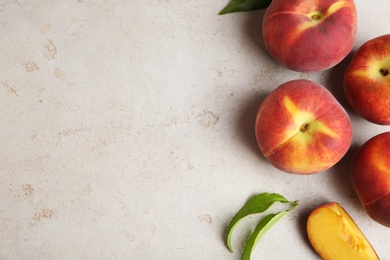 Photo of Fresh peaches and leaves on grey stone surface, top view with space for text