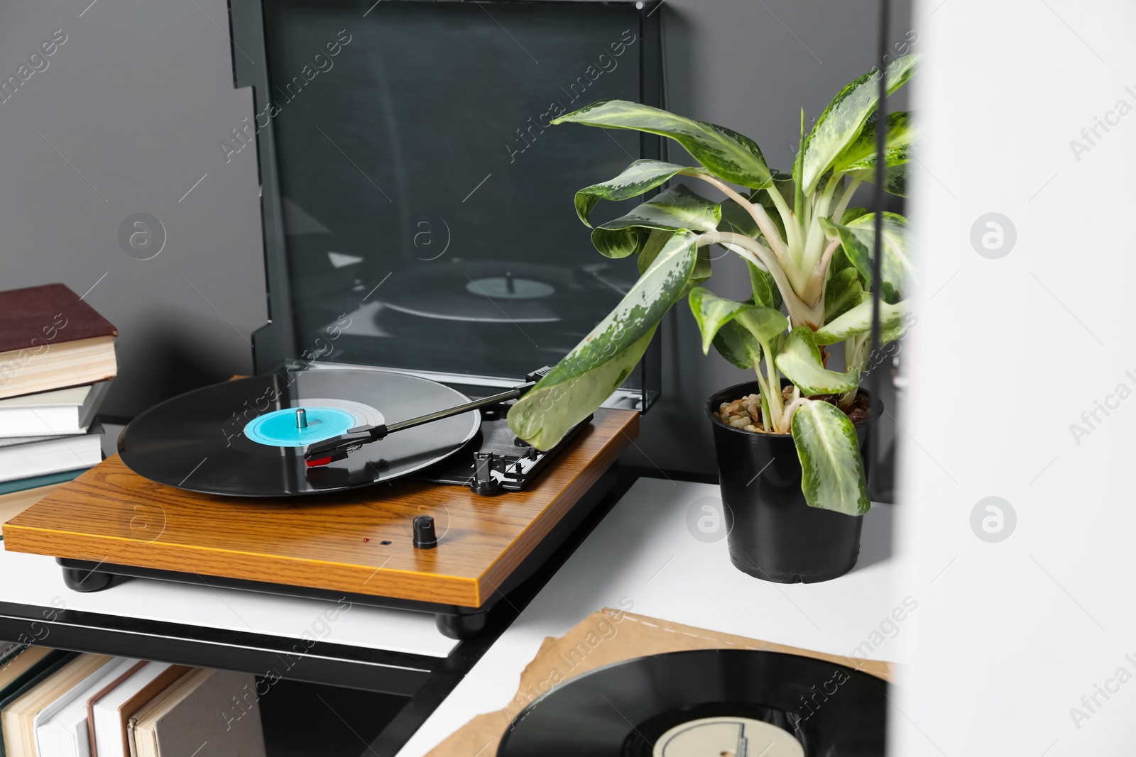 Photo of Stylish turntable with vinyl disc near grey wall in room