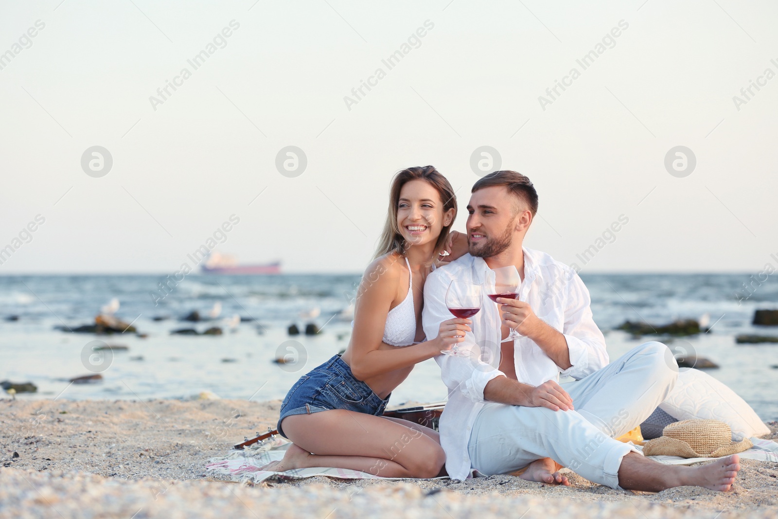 Photo of Young couple with glasses of wine on beach