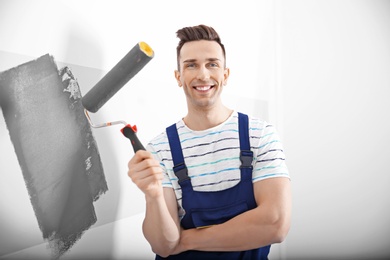 Photo of Young male decorator painting wall in room