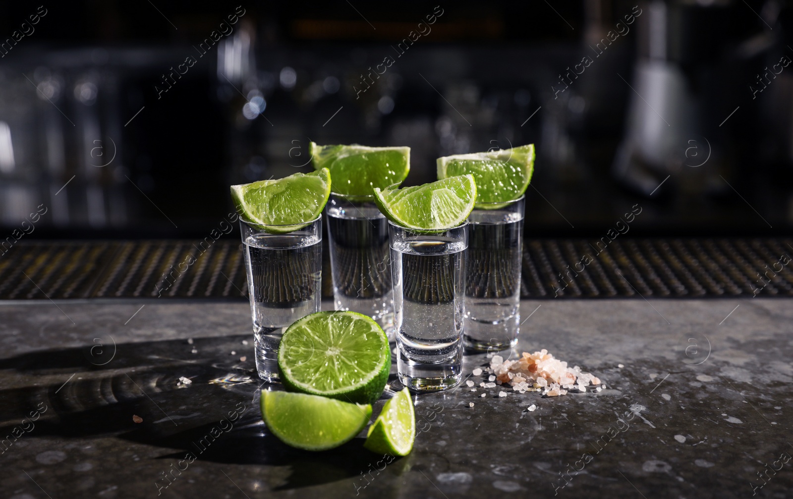 Photo of Mexican Tequila shots, lime slices and salt on bar counter