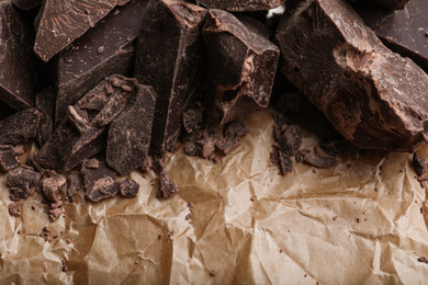 Photo of Pieces of dark chocolate on parchment, closeup