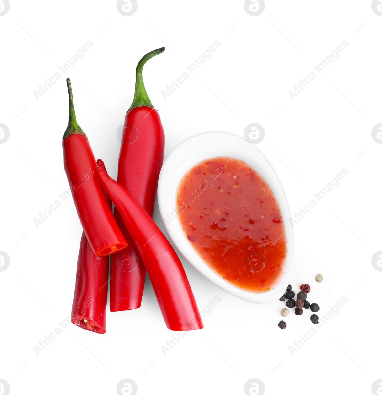 Photo of Spicy chili sauce, peppers and peppercorns isolated on white, top view