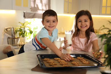 Photo of Cute little children with cookies and milk in kitchen. Cooking pastry