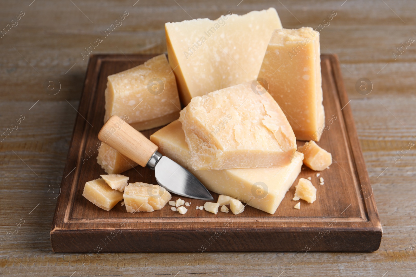 Photo of Delicious parmesan cheese with knife on wooden table