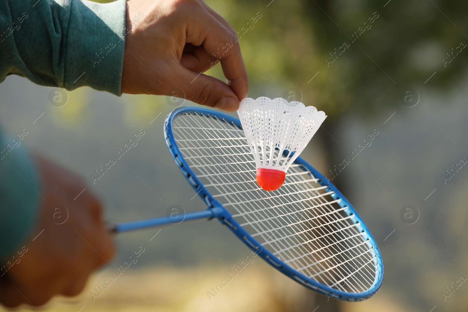 Photo of Man playing badminton outdoors on sunny day, closeup