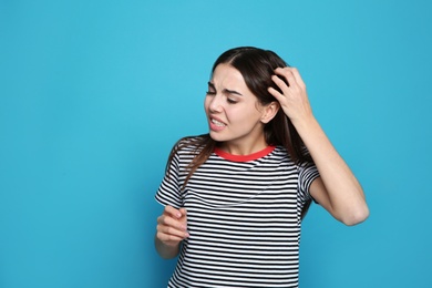 Photo of Young woman scratching head on color background. Annoying itch