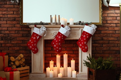 Photo of Decorative fireplace with Christmas stocking and gifts in stylish room interior
