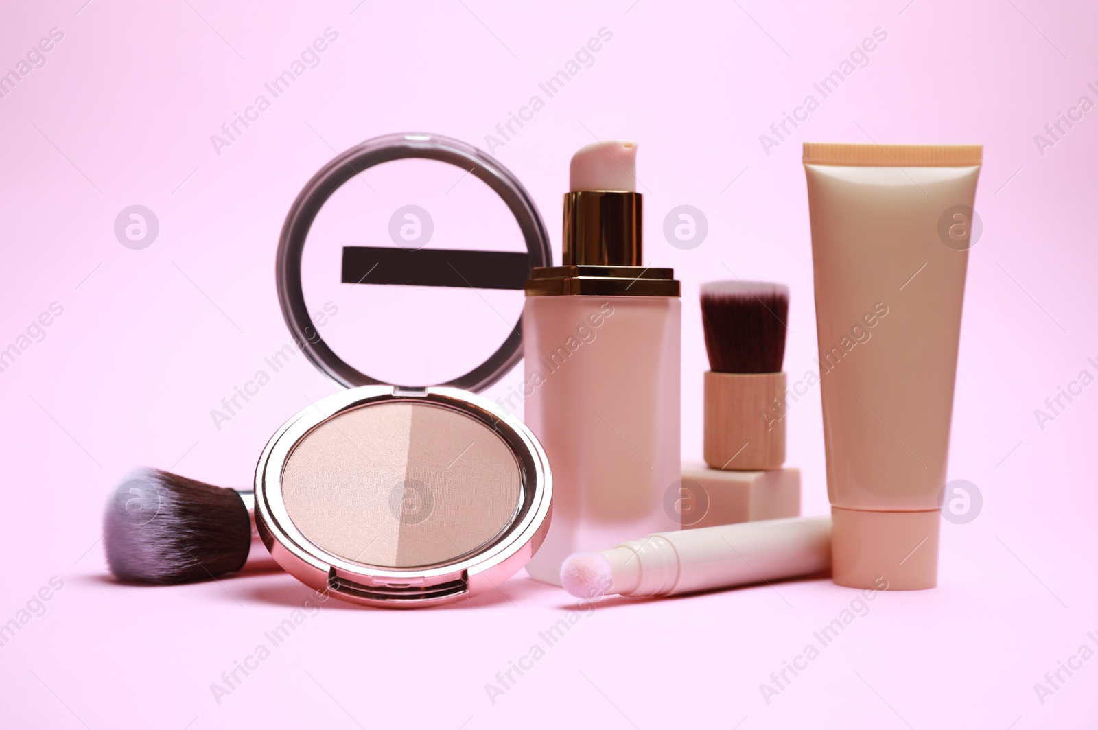 Photo of Face powder and other decorative cosmetic products on pink background