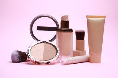 Photo of Face powder and other decorative cosmetic products on pink background