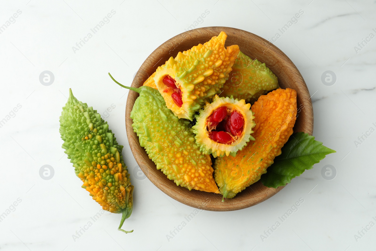 Photo of Fresh bitter melons on white marble table, flat lay