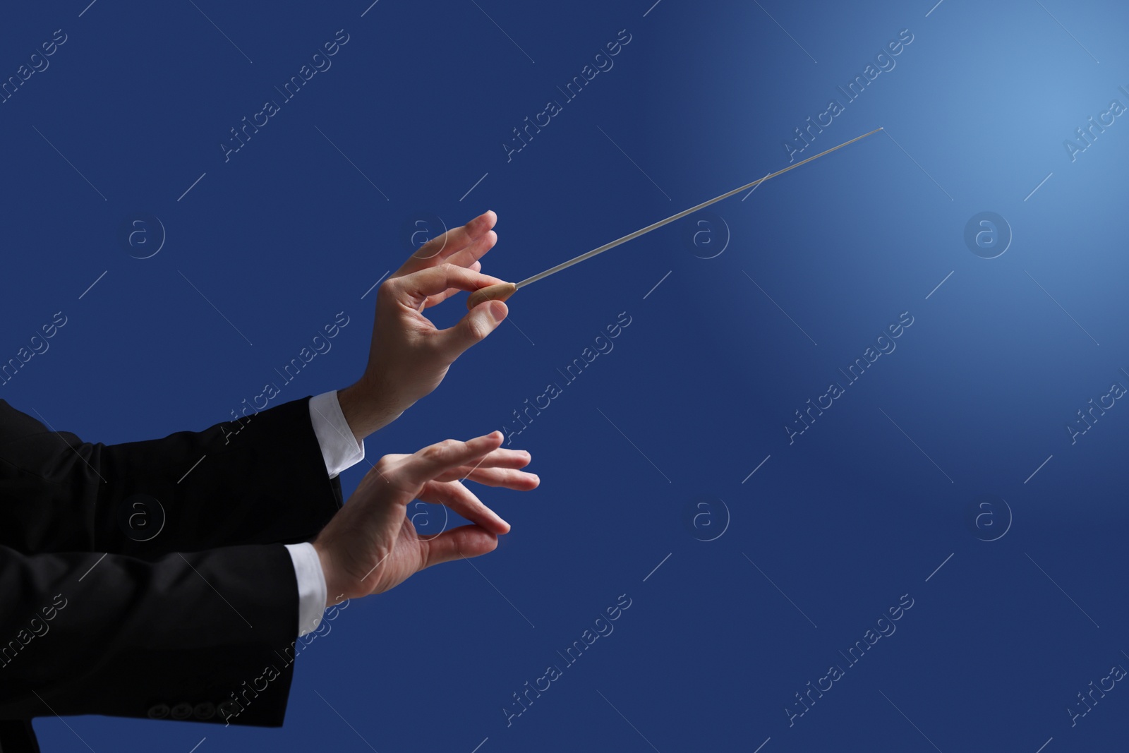 Photo of Professional conductor with baton on blue background, closeup