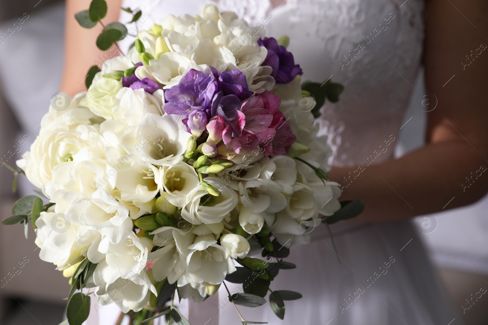 Photo of Bride holding beautiful bouquet with spring freesia flowers, closeup