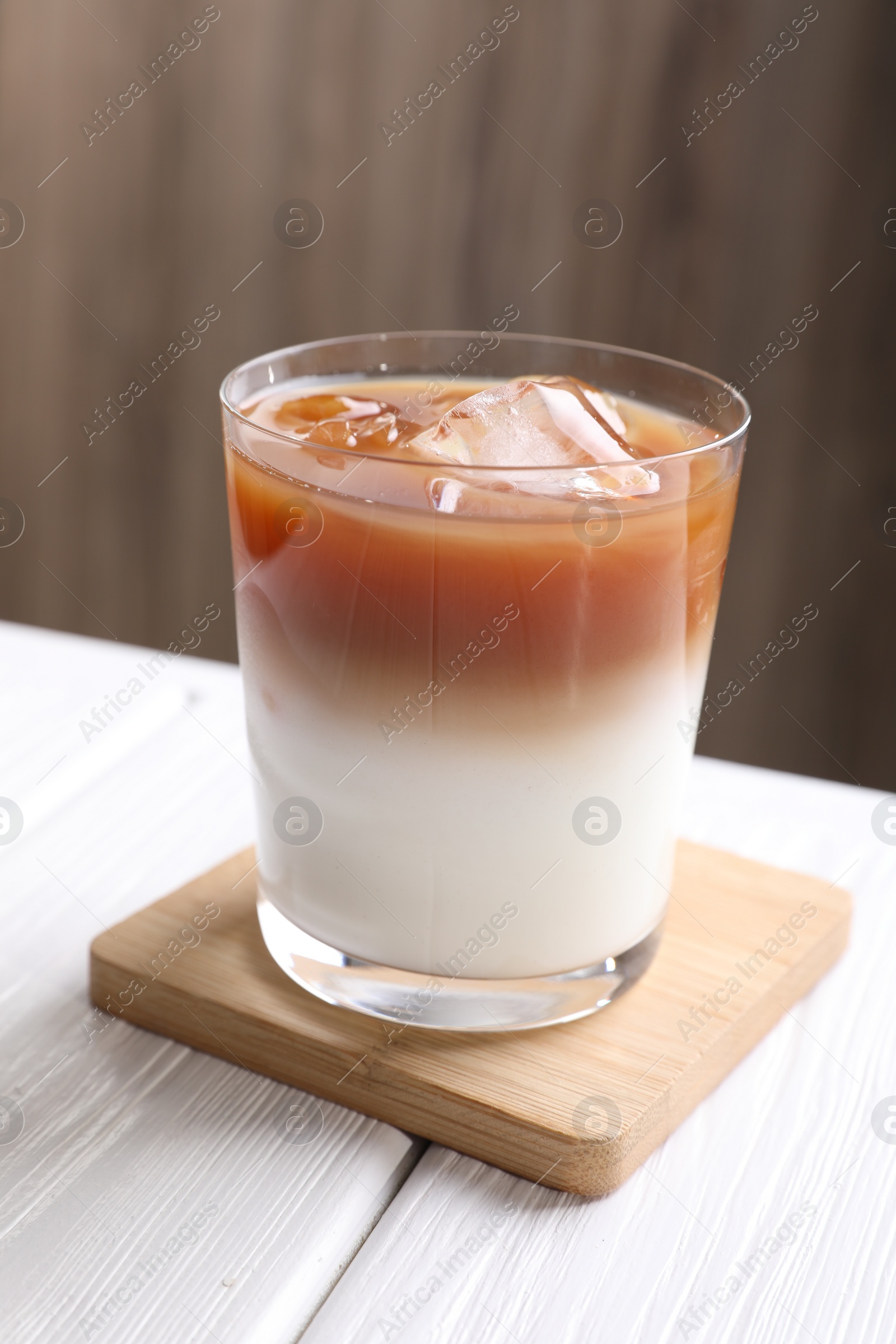 Photo of Glass of iced coffee on white wooden table