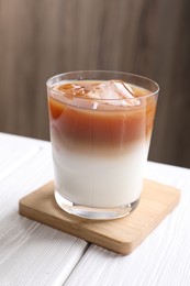 Photo of Glass of iced coffee on white wooden table