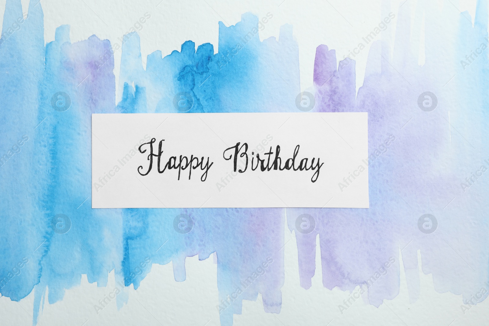 Photo of Card with words HAPPY BIRTHDAY on watercolor painting, top view