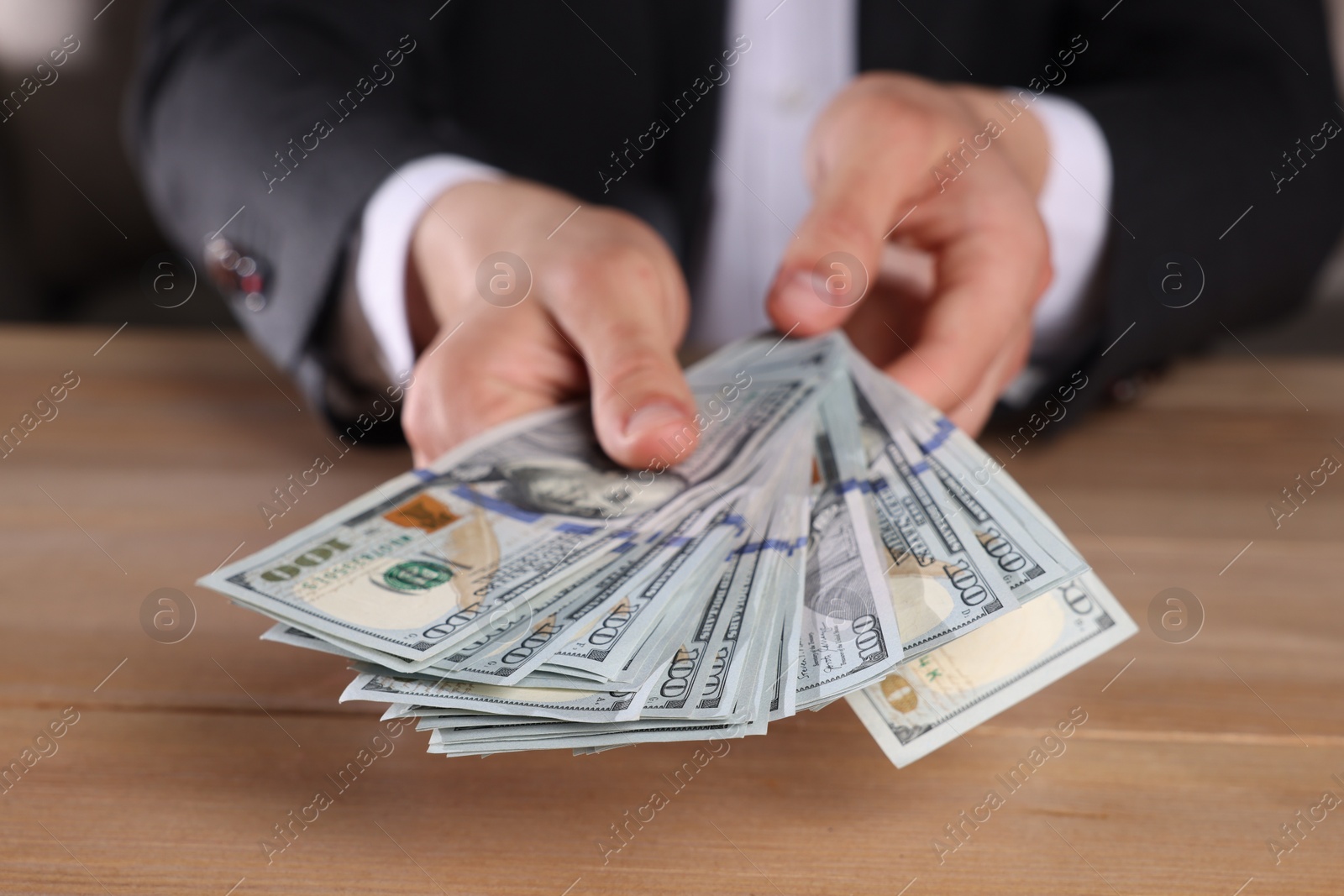 Photo of Money exchange. Man counting dollar banknotes at wooden table, closeup