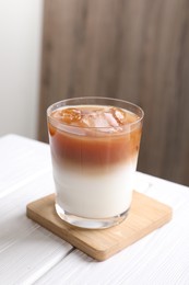 Photo of Glass of iced coffee on white wooden table