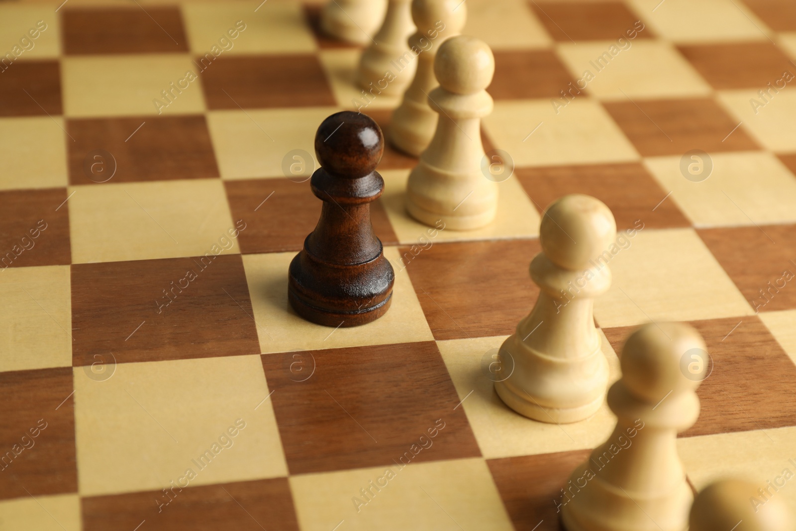 Photo of Black pawn among white ones on chess board, closeup. Concept of racism
