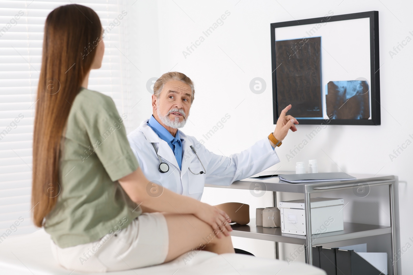 Photo of Orthopedist showing X-ray picture to patient in clinic