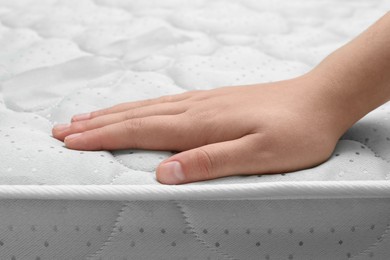 Woman touching new soft mattress, closeup view