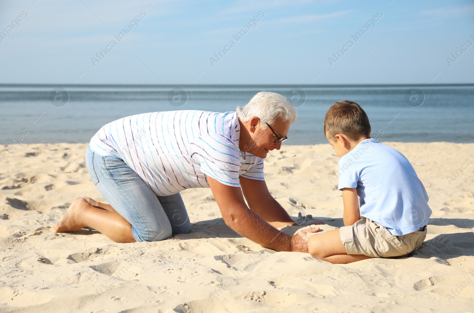 Photo of Cute little boy with grandfather spending time together on sea beach