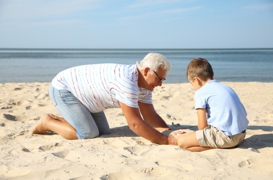 Photo of Cute little boy with grandfather spending time together on sea beach