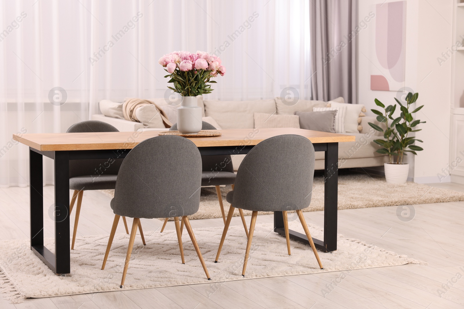 Photo of Table, chairs and vase with peonies in stylish dining room