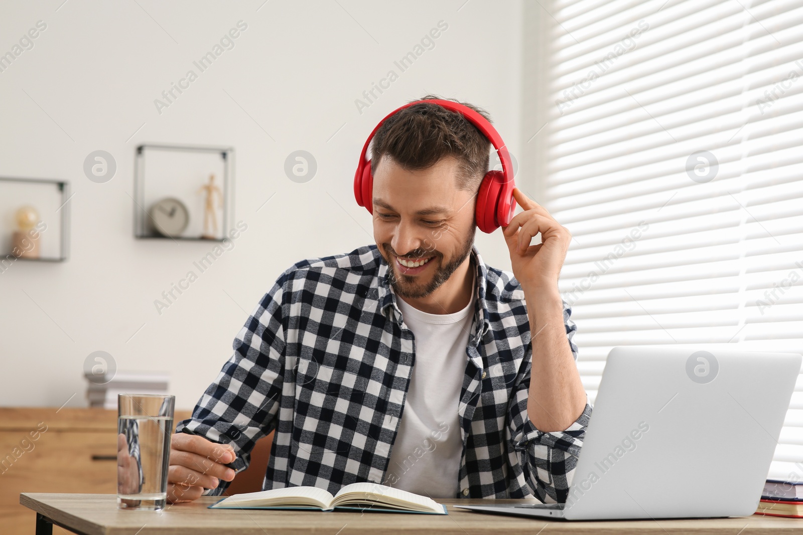 Photo of Man in headphones studying on laptop at home. Online translation course