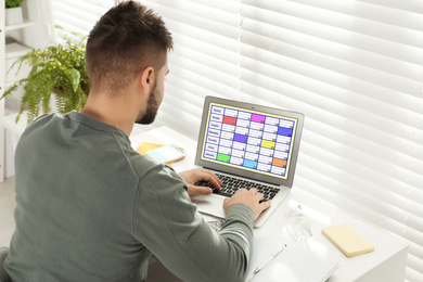 Young man using calendar app on laptop in office