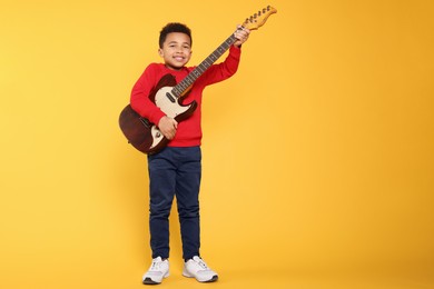 African-American boy with electric guitar on yellow background. Space for text