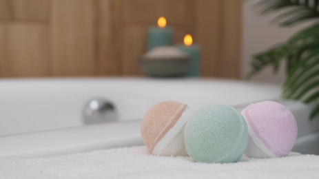 Photo of Colorful bath bombs on white towel in bathroom. Space for text