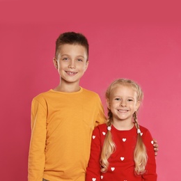 Cute little children in warm clothes on pink background. Winter season